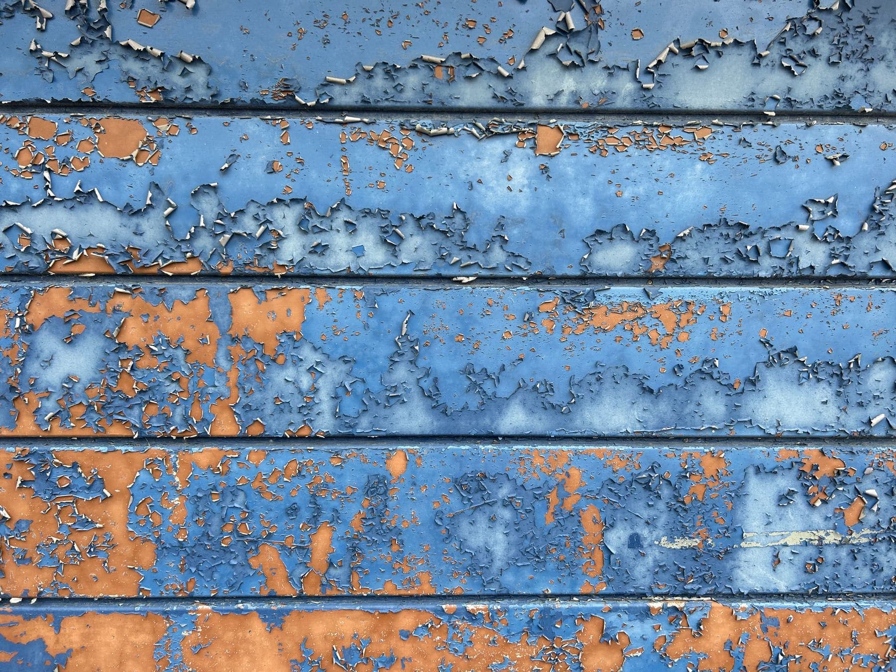 House cladding with faded, peeling paint before repainting