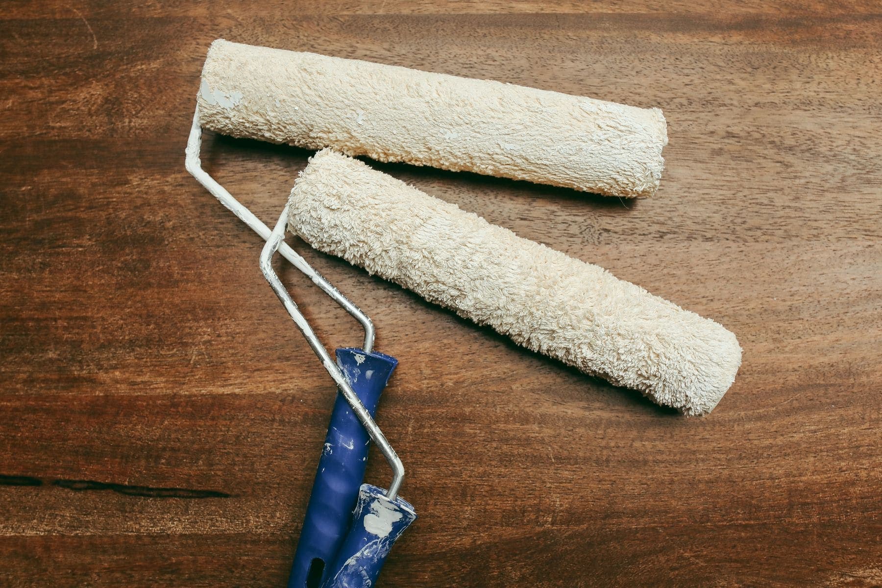 Two paint rollers laid out on a timber bench