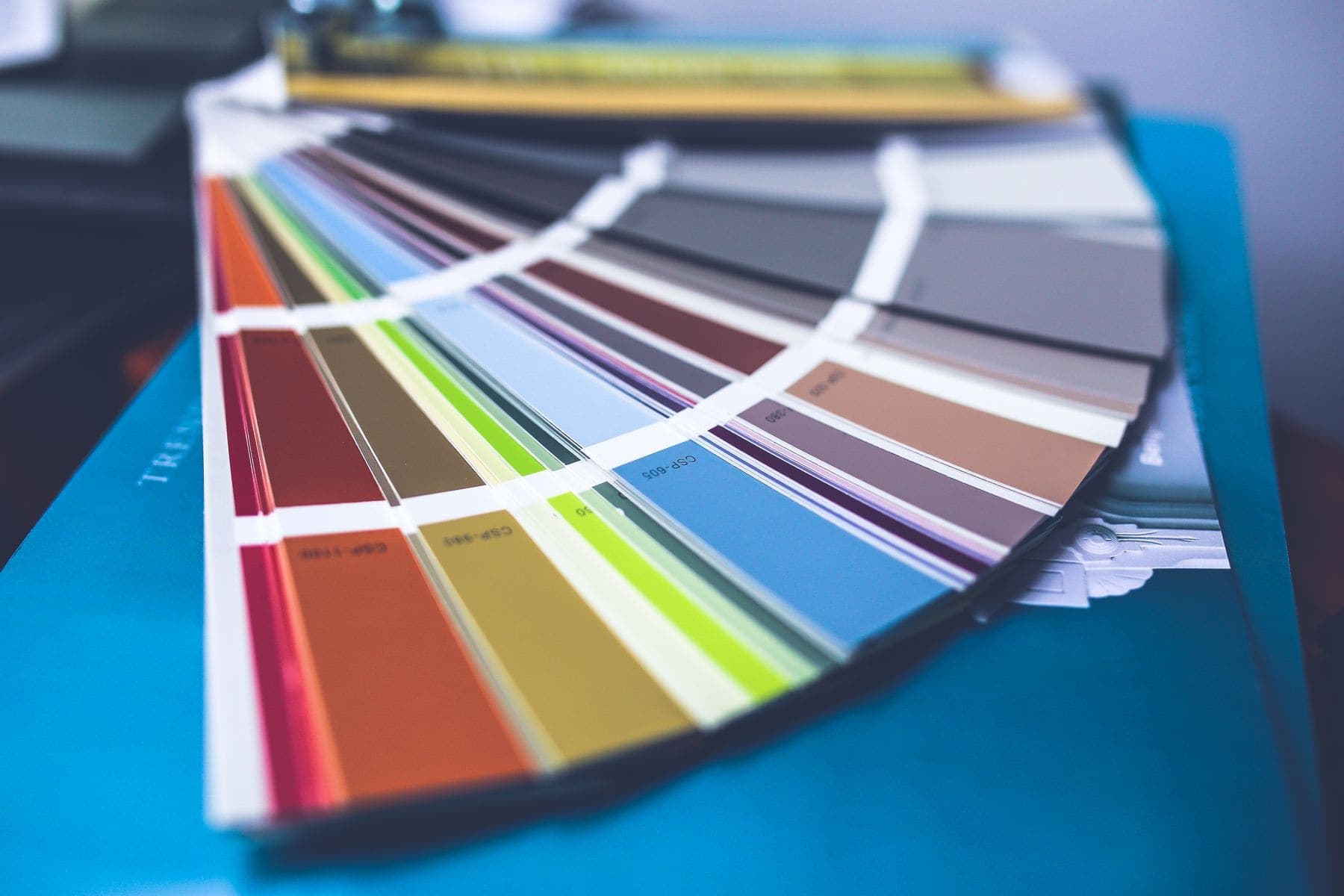 Fanned paint colour swatch deck spread across a table