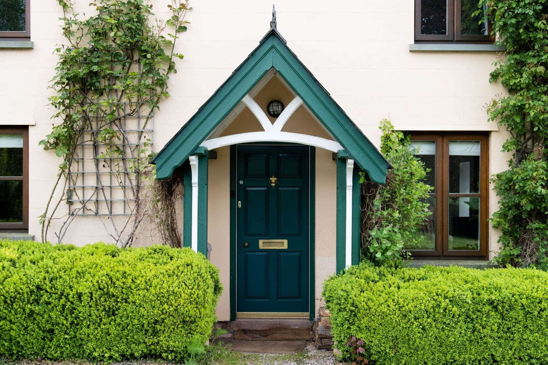 Newly painted teal front door framed by a porch and greenery